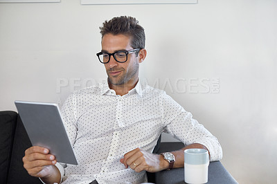 Buy stock photo Cropped shot of a handsome businessman using his digital tablet at work