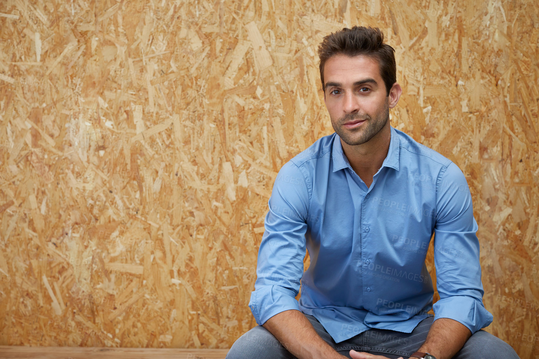 Buy stock photo Cropped shot of a handsome young man posing against a wooden background