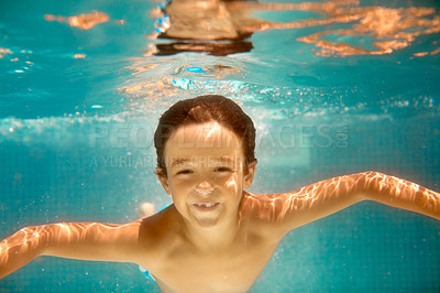 Buy stock photo Underwater shot of a little boy swimming in a pool