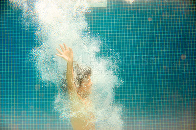 Buy stock photo Underwater shot of a little boy swimming in a pool