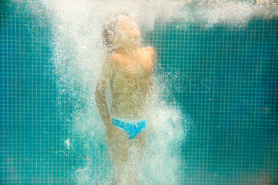 Buy stock photo Underwater shot of a little boy swimming in a pool