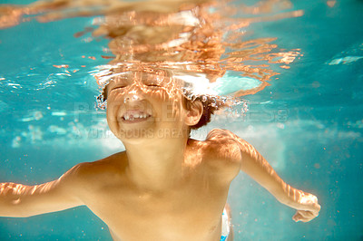 Buy stock photo Underwater shot of a little boy swimming in a pool
