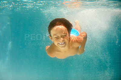 Buy stock photo Underwater shot of a little boy swimming in a pool