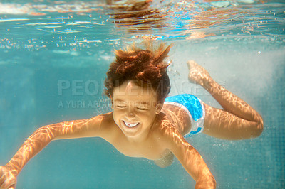 Buy stock photo Underwater shot of a little boy swimming in a pool