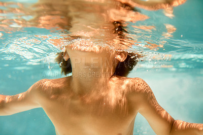 Buy stock photo Underwater shot of a little boy swimming in a pool