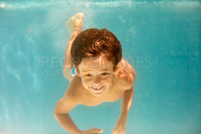 Buy stock photo Underwater shot of a little boy swimming in a pool
