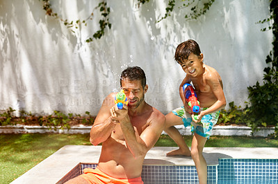 Buy stock photo Portrait of a father and his son playing with water guns at the swimming pool