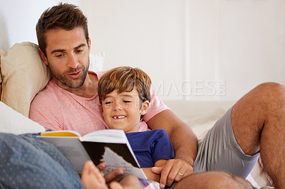 Buy stock photo Shot of a father and son reading and relaxing on the sofa at home