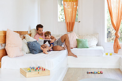 Buy stock photo Shot of a father and son reading and relaxing on the sofa at home