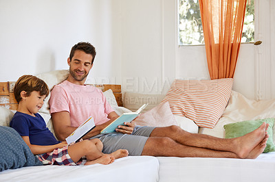 Buy stock photo Shot of a father and son reading and relaxing on the sofa at home