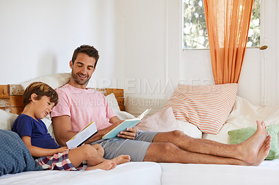 Buy stock photo Shot of a father and son reading and relaxing on the sofa at home