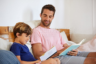 Buy stock photo Shot of a father and son reading and relaxing on the sofa at home
