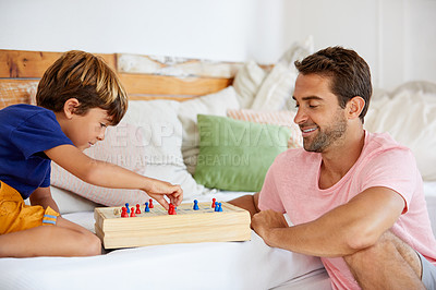 Buy stock photo Shot of a father and son playing a board game in the living room at home