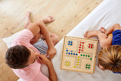 Buy stock photo High angle shot of a father and son playing a board game in the living room at home