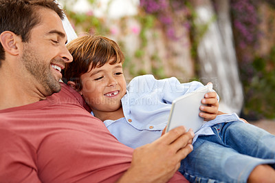 Buy stock photo Shot of a father and son using a digital tablet while relaxing together outside