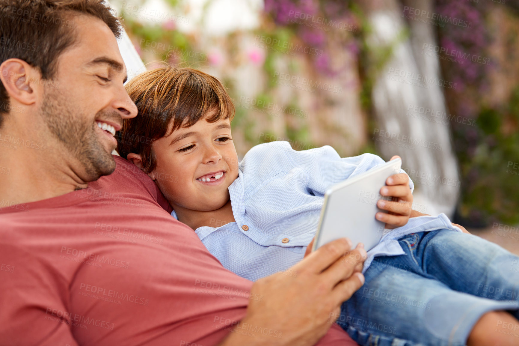 Buy stock photo Shot of a father and son using a digital tablet while relaxing together outside