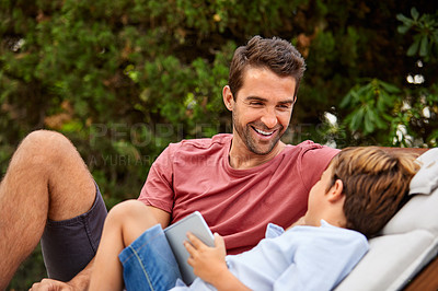 Buy stock photo Shot of a father and son using a digital tablet while relaxing together outside