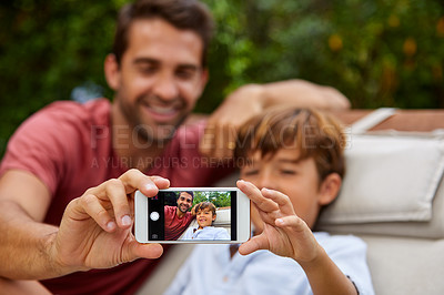 Buy stock photo Shot of a father an son taking a selfie together outside