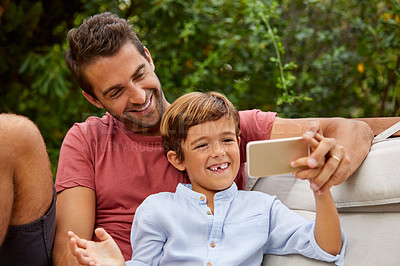 Buy stock photo Shot of a father an son taking a selfie together outside