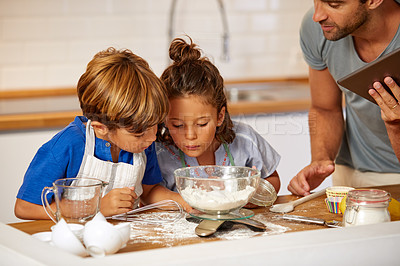 Buy stock photo Cropped shot of a father helping his son and daughter bake at home