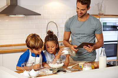Buy stock photo Cropped shot of a father helping his son and daughter bake at home