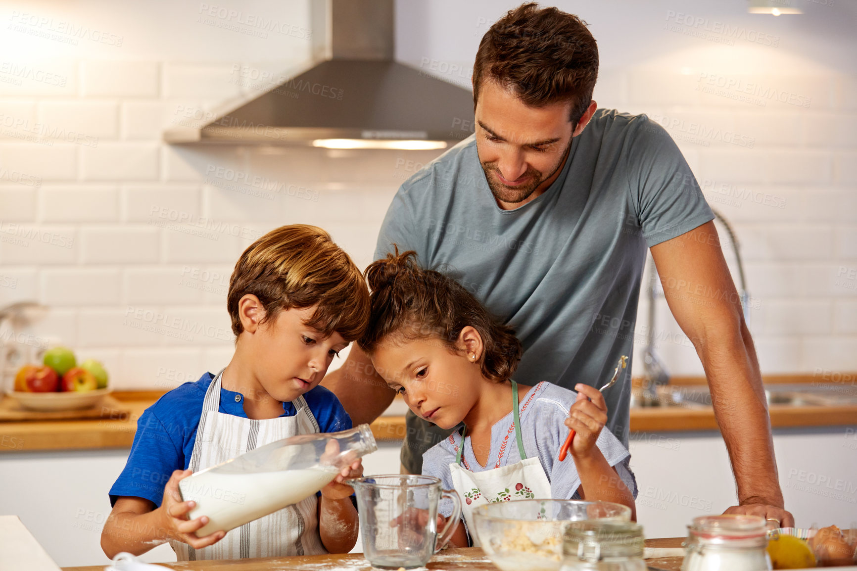 Buy stock photo Cropped shot of a father helping his son and daughter bake in the kitchen at home
