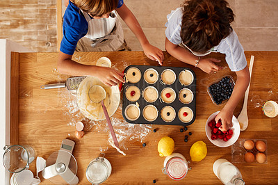Buy stock photo High angle shot of a brother and sister adding fruit to their batter before it gets baked in the oven at home
