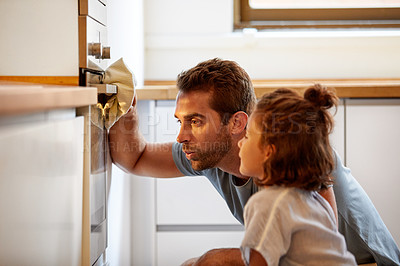 Buy stock photo Cropped shot of a father and daughter looking at what they had baked in the oven at home