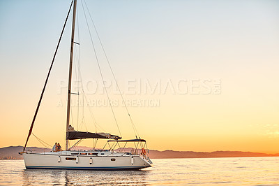 Buy stock photo Shot of a young couple going for an ocean cruise at sunset