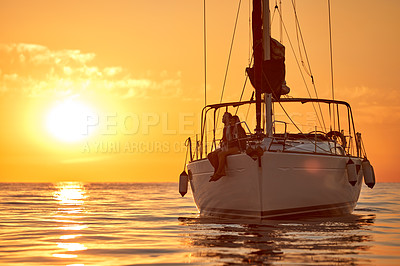 Buy stock photo Shot of a young couple going for an ocean cruise at sunset