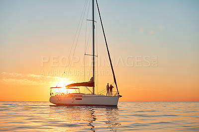 Buy stock photo Shot of a young couple going for an ocean cruise at sunset