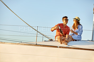 Buy stock photo Shot of a young couple drinking champagne together on an ocean cruise