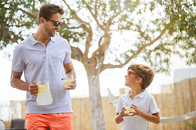 Buy stock photo Shot of a young man and his adorable son spending a day together outdoors with some lemonade