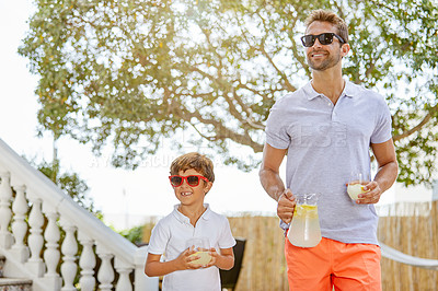 Buy stock photo Shot of a young man and his adorable son spending a day together outdoors with some lemonade