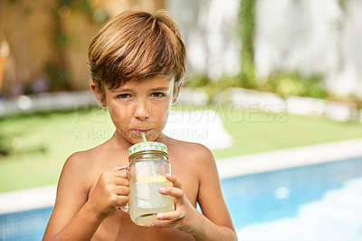 Buy stock photo Portrait of an adorable little boy drinking lemonade next to a swimming pool