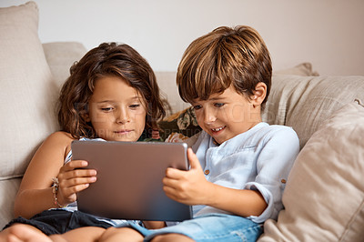 Buy stock photo Shot of a little girl and boy sharing a digital tablet at home