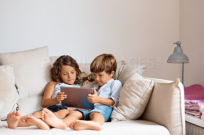 Buy stock photo Shot of a little girl and boy sharing a digital tablet at home