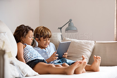 Buy stock photo Shot of a little girl and boy sharing a digital tablet at home