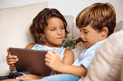 Buy stock photo Shot of a little girl and boy sharing a digital tablet at home