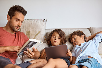 Buy stock photo Shot of a little girl and boy using a digital tablet while sitting with their father
