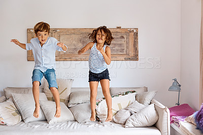 Buy stock photo Shot of a little girl and boy jumping on the sofa at home