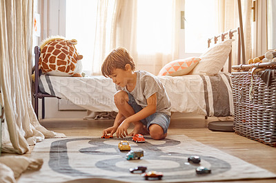 Buy stock photo Shot of a little boy playing with his toys at home