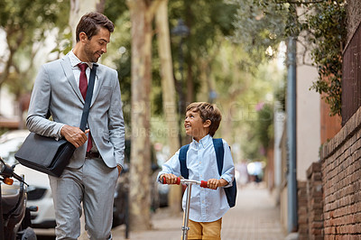 Buy stock photo Shot of a little boy riding his scooter with his father by his side