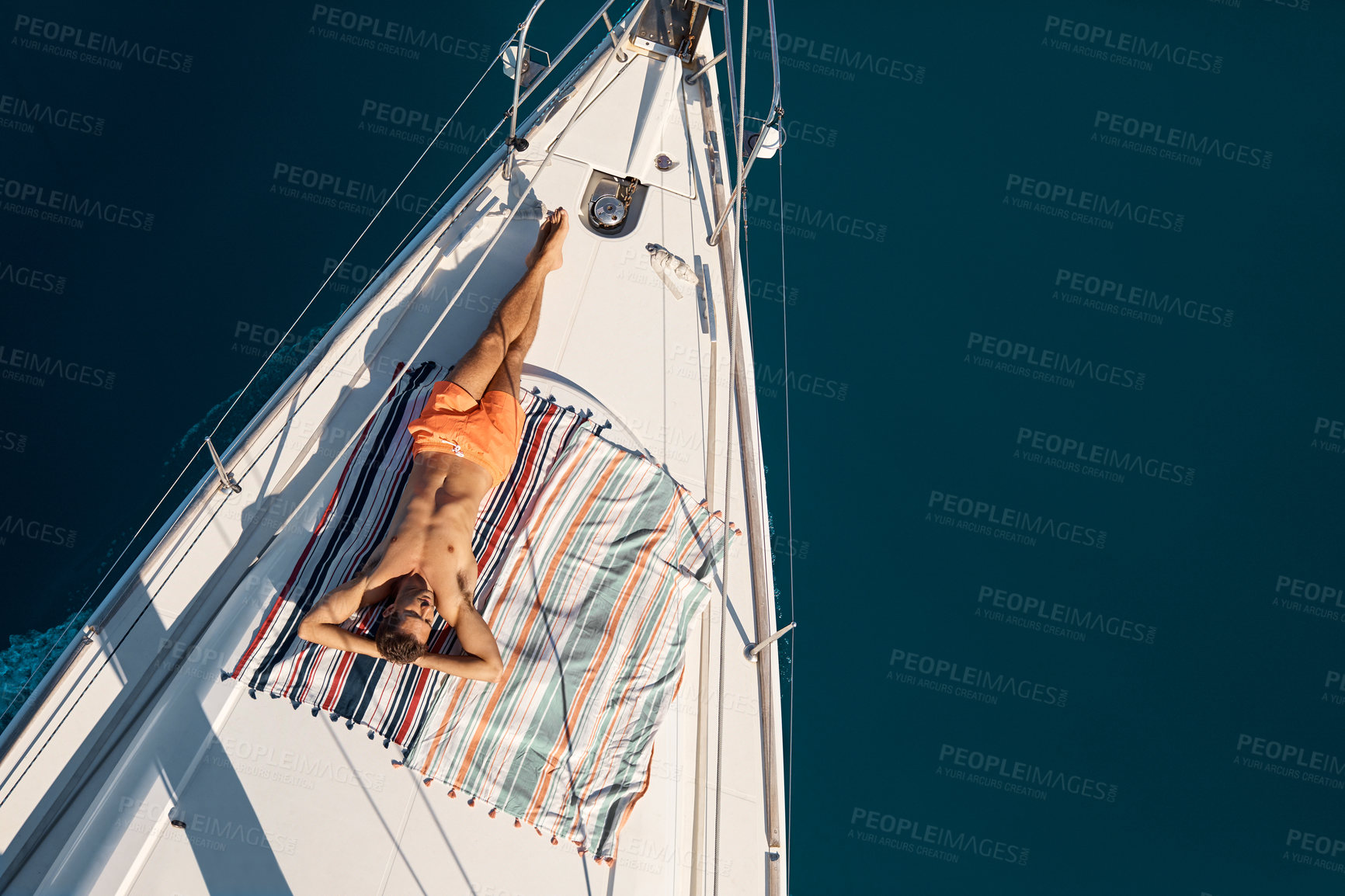 Buy stock photo High angle shot of a handsome young man tanning while enjoying a yacht cruise