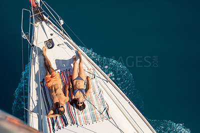 Buy stock photo High angle shot of an affectionate young couple tanning while enjoying a yacht cruise