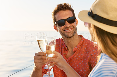 Buy stock photo Shot of a young couple drinking champagne together on an ocean cruise