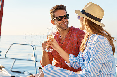 Buy stock photo Shot of a young couple drinking champagne together on an ocean cruise