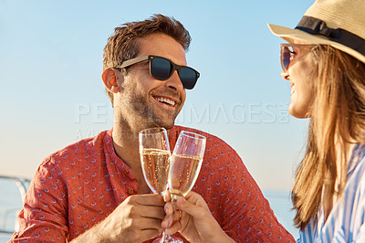 Buy stock photo Shot of a young couple drinking champagne together on an ocean cruise