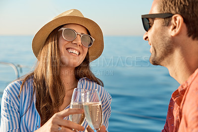 Buy stock photo Shot of a young couple drinking champagne together on an ocean cruise