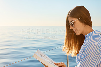 Buy stock photo Shot of a beautiful young woman reading a book an ocean cruise